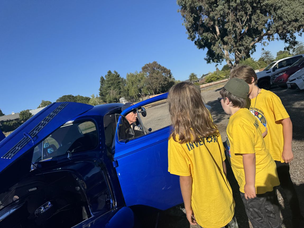 A young person learning automotive skills on a classic car