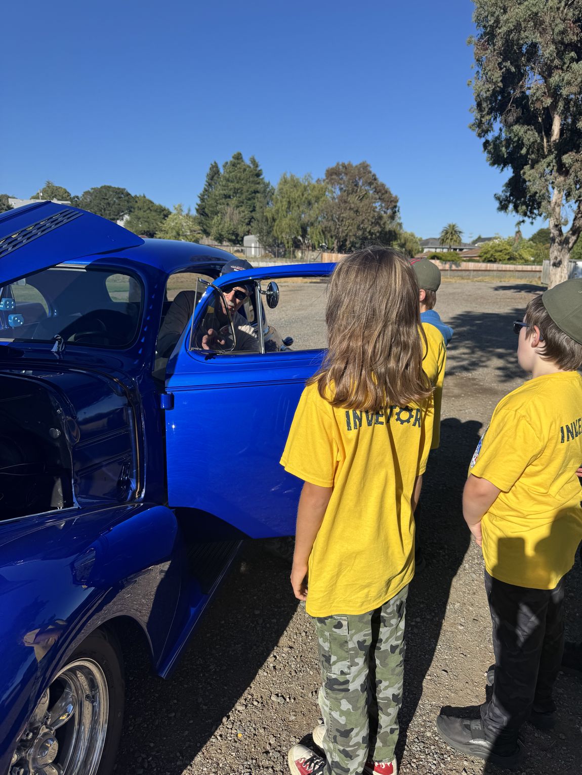 Kids gathered around a classic hot rod at a community event